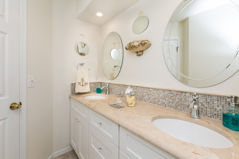 Exemple d'une salle de bain tendance de taille moyenne avec un placard à porte shaker, des portes de placard blanches, un carrelage blanc, un carrelage métro, un mur blanc, un sol en carrelage de porcelaine, un lavabo encastré et un plan de toilette en marbre.