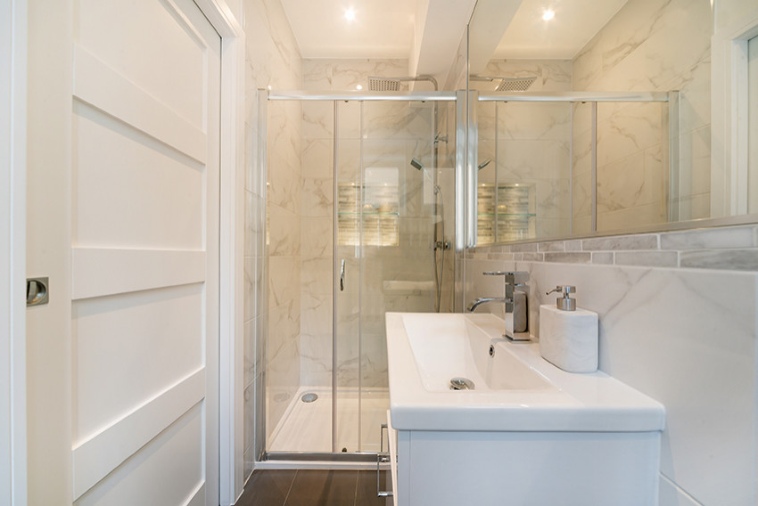 Inspiration for a small contemporary shower room bathroom with flat-panel cabinets, white cabinets, a walk-in shower, white tiles, white walls, ceramic flooring, a built-in sink, grey floors, a sliding door, a wall niche, a single sink and a freestanding vanity unit.