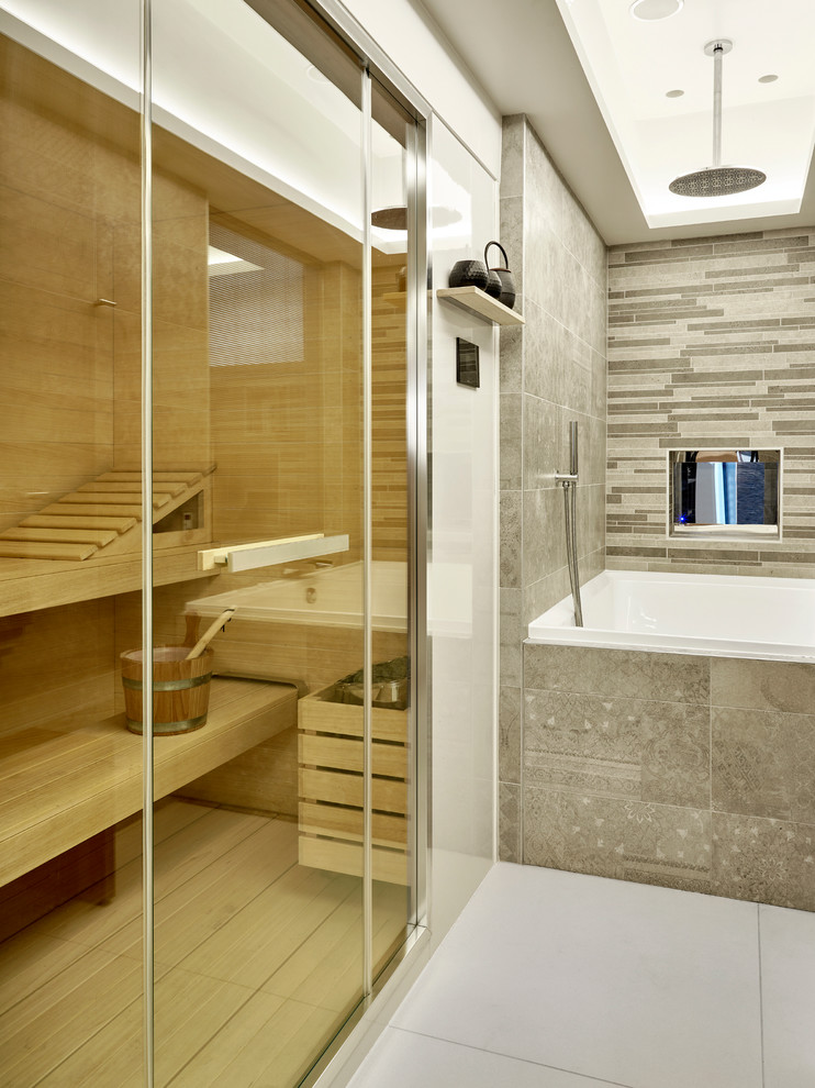 На фото: ванная комната в стиле модернизм с плоскими фасадами, накладной ванной, душем над ванной, серой плиткой, керамогранитной плиткой и полом из керамогранита с