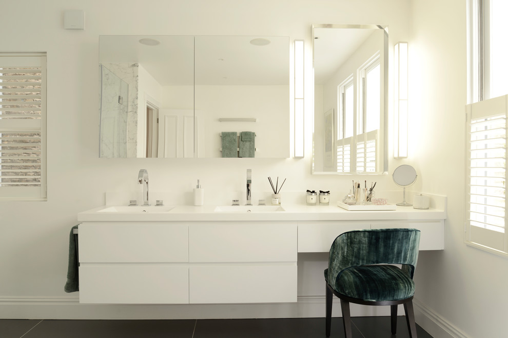 Foto på ett mellanstort funkis badrum, med släta luckor, vita skåp, vita väggar, ett undermonterad handfat och svart golv