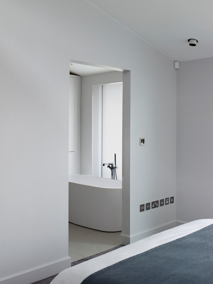 Photo of a large contemporary ensuite bathroom in London with flat-panel cabinets, blue cabinets, a wall mounted toilet, marble tiles, yellow walls, marble worktops, grey floors and white worktops.