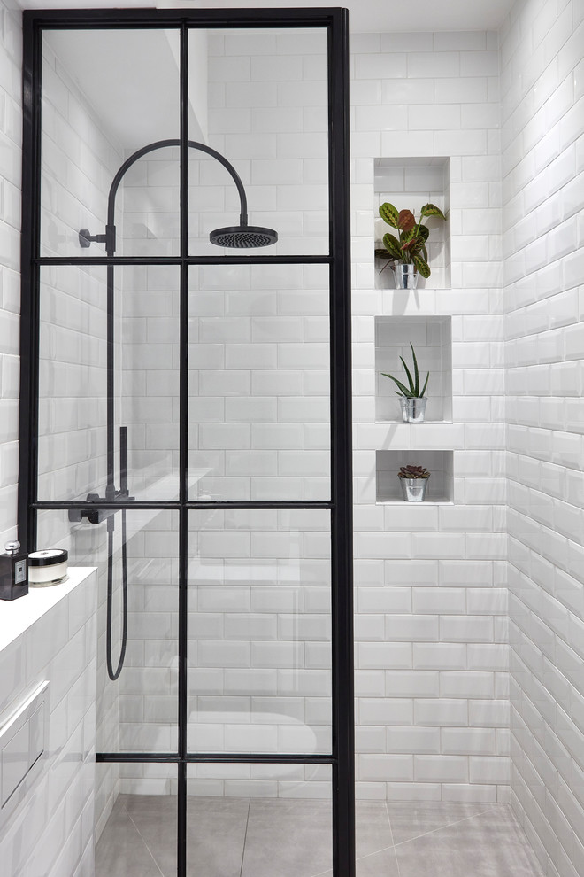 This is an example of an industrial family bathroom in London with a freestanding bath, a walk-in shower, a wall mounted toilet, grey tiles, porcelain tiles, grey walls, cement flooring, a pedestal sink, grey floors and an open shower.