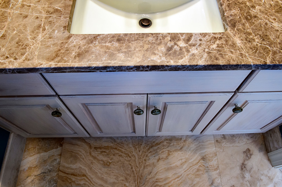This is an example of a classic bathroom in Charleston with light wood cabinets, blue walls, travertine flooring, a submerged sink and granite worktops.