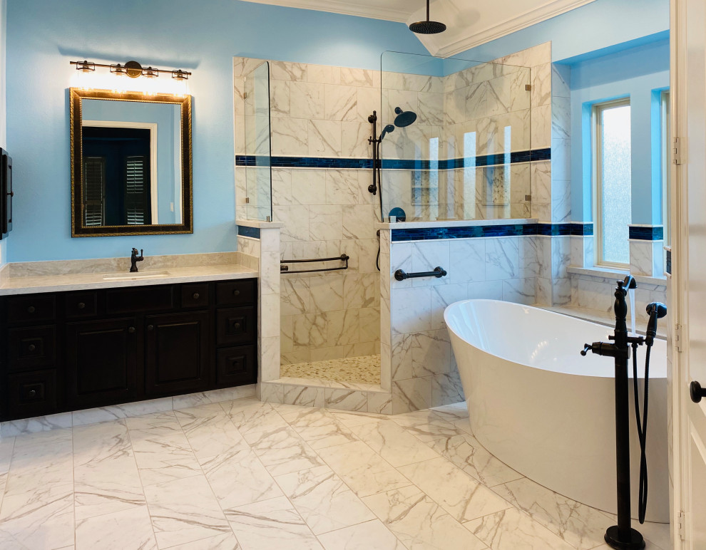 Design ideas for an expansive traditional ensuite bathroom in Houston with raised-panel cabinets, dark wood cabinets, a freestanding bath, a walk-in shower, multi-coloured tiles, porcelain tiles, blue walls, porcelain flooring, a submerged sink, engineered stone worktops, multi-coloured floors, an open shower, multi-coloured worktops, an enclosed toilet, double sinks, a built in vanity unit and a vaulted ceiling.