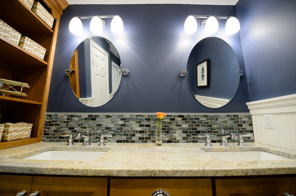 Réalisation d'une salle de bain tradition en bois brun de taille moyenne pour enfant avec un placard avec porte à panneau encastré, une baignoire posée, WC à poser, un carrelage bleu, des plaques de verre, un mur bleu, un sol en carrelage de céramique, un lavabo encastré et un plan de toilette en granite.
