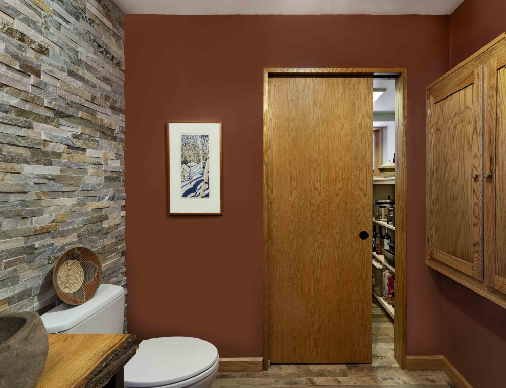 Exemple d'un petit WC et toilettes tendance avec un placard en trompe-l'oeil, des portes de placard noires, un carrelage orange, un plan de toilette en bois, WC à poser, un sol en bois brun et une vasque.