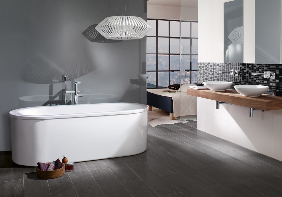 Cette image montre une salle de bain traditionnelle avec une vasque, une baignoire indépendante et un mur gris.