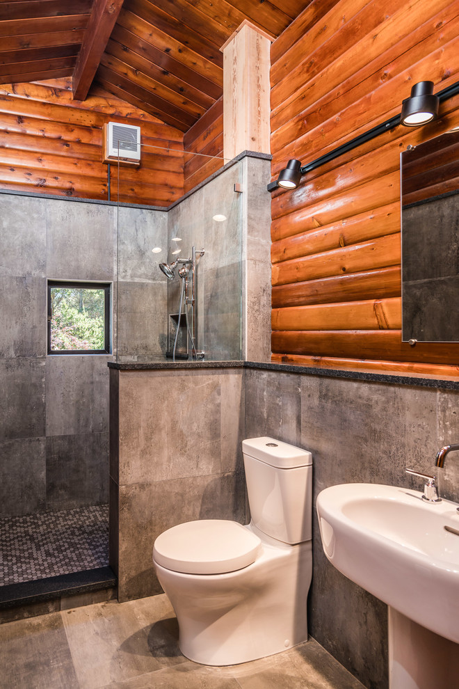 Exempel på ett litet rustikt en-suite badrum, med en öppen dusch, grå kakel, cementkakel, klinkergolv i keramik, ett piedestal handfat, grått golv, med dusch som är öppen, en toalettstol med separat cisternkåpa, bruna väggar och bänkskiva i akrylsten