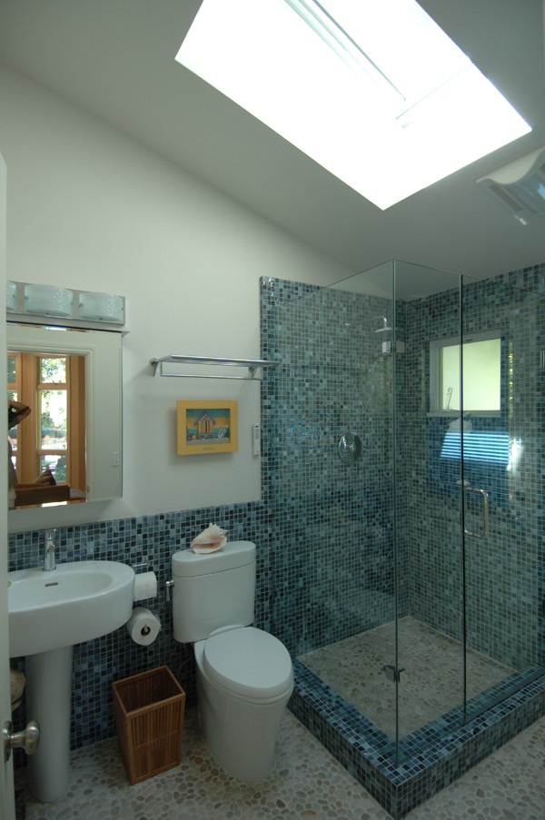 Ejemplo de cuarto de baño tropical con lavabo con pedestal, ducha esquinera, sanitario de dos piezas, baldosas y/o azulejos azules y baldosas y/o azulejos de vidrio