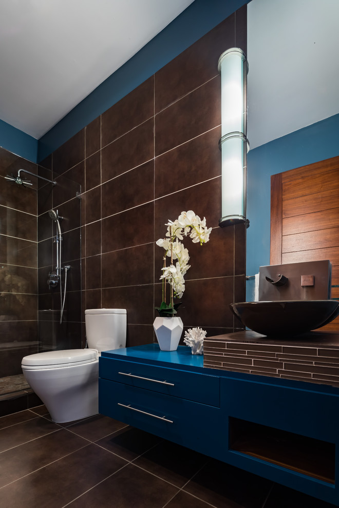 На фото: ванная комната среднего размера в стиле модернизм с фасадами островного типа, коричневыми фасадами, угловым душем, унитазом-моноблоком, коричневой плиткой, керамической плиткой, синими стенами, полом из керамической плитки, душевой кабиной, консольной раковиной, столешницей из плитки, коричневым полом, душем с раздвижными дверями и коричневой столешницей с