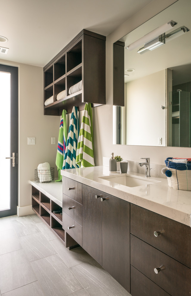 Cette image montre une salle de bain design en bois foncé avec un placard à porte plane, un mur blanc, un lavabo encastré et un sol gris.
