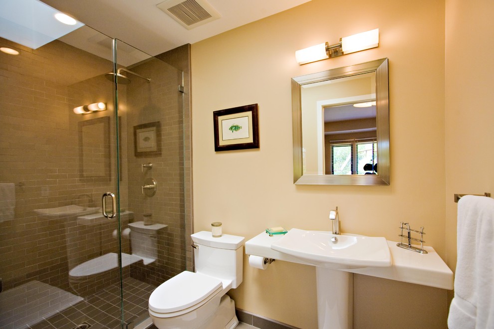 Inspiration för ett litet funkis badrum, med ett piedestal handfat, en dusch i en alkov, en toalettstol med hel cisternkåpa, brun kakel, porslinskakel, gula väggar och klinkergolv i porslin