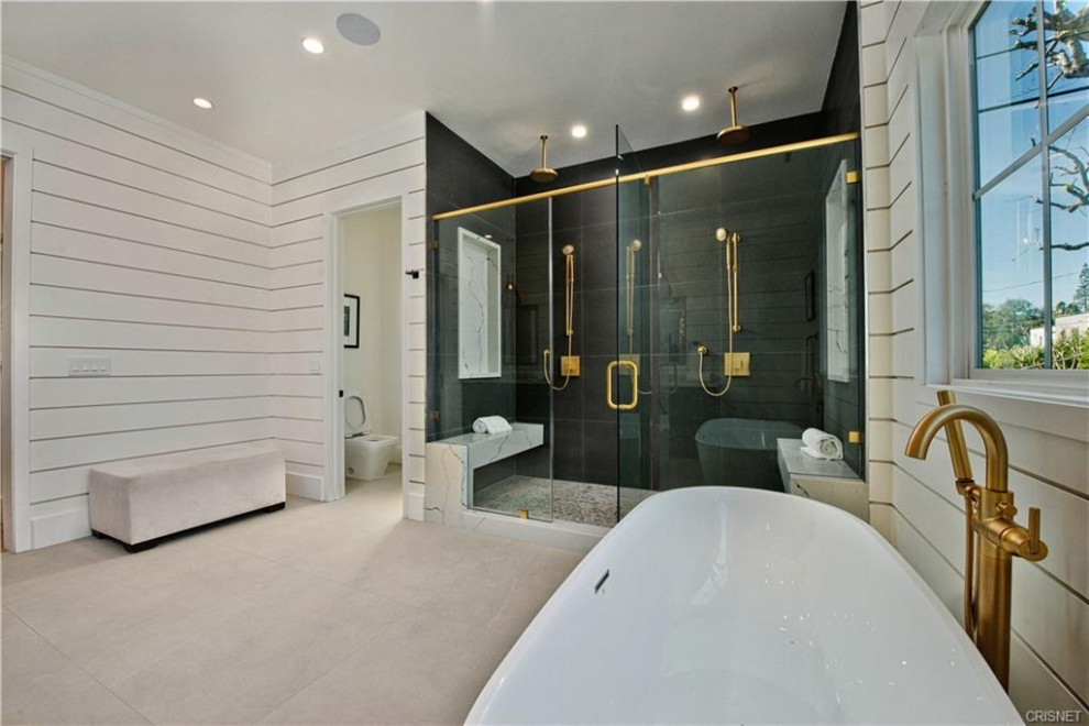 Cette image montre une grande salle de bain principale minimaliste avec une baignoire indépendante, une douche double, un carrelage noir, un mur blanc, un sol blanc, une cabine de douche à porte battante, un banc de douche et du lambris de bois.