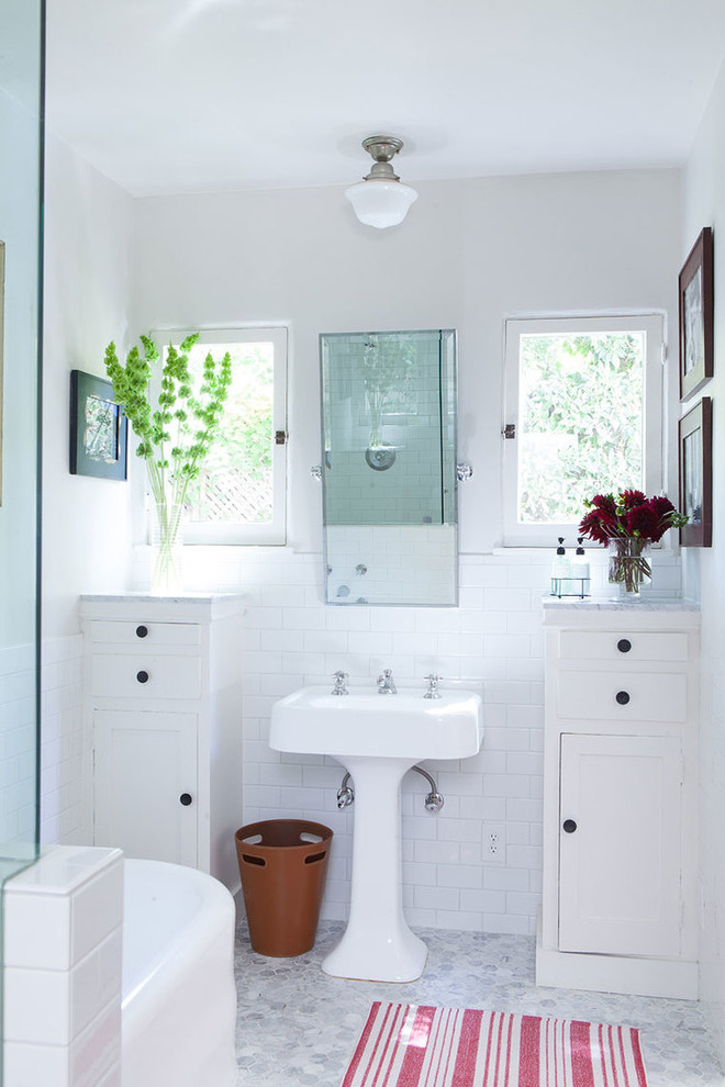 На фото: ванная комната в морском стиле с раковиной с пьедесталом, фасадами в стиле шейкер, белыми фасадами, отдельно стоящей ванной, белой плиткой, плиткой кабанчик, белыми стенами и окном с
