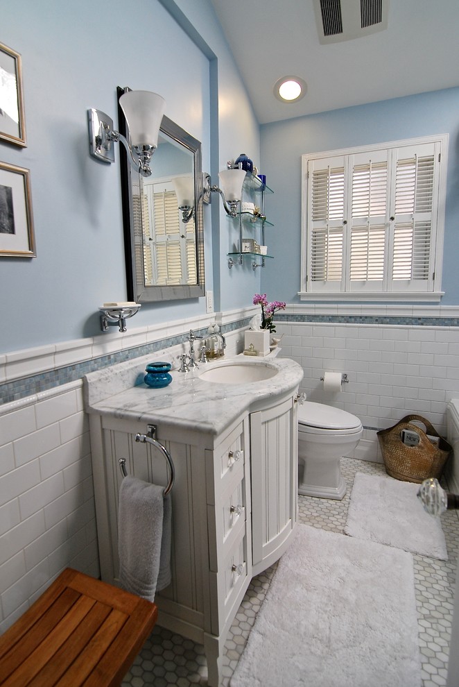 Inredning av ett modernt litet en-suite badrum, med ett undermonterad handfat, luckor med infälld panel, vita skåp, marmorbänkskiva, ett hörnbadkar, en hörndusch, en toalettstol med hel cisternkåpa, blå kakel, tunnelbanekakel, blå väggar och marmorgolv