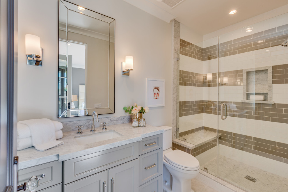 На фото: ванная комната в стиле неоклассика (современная классика) с фасадами с утопленной филенкой, серыми фасадами, угловым душем, раздельным унитазом, коричневой плиткой, белой плиткой, плиткой кабанчик, белыми стенами, душевой кабиной, врезной раковиной, бежевым полом, душем с распашными дверями и серой столешницей с