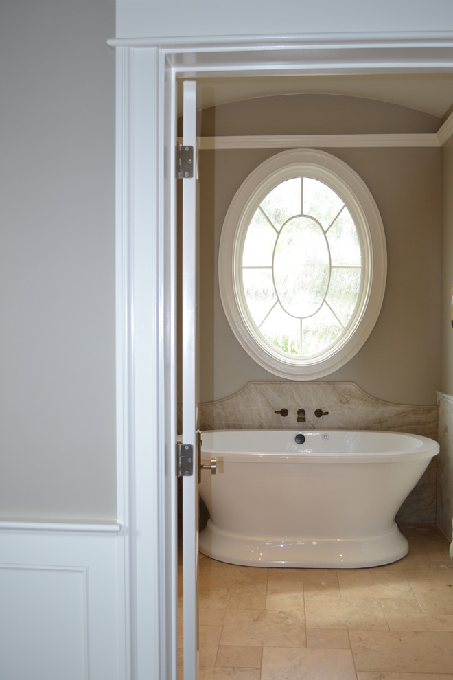 Cette image montre une salle de bain chalet avec une baignoire indépendante, un carrelage beige, mosaïque, un mur beige et un sol en calcaire.