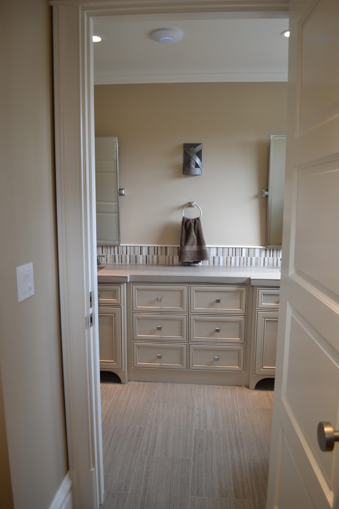 Idée de décoration pour une salle de bain chalet avec un placard à porte affleurante, des portes de placard grises, un plan de toilette en marbre, un carrelage beige, mosaïque, un mur beige et un sol en carrelage de porcelaine.
