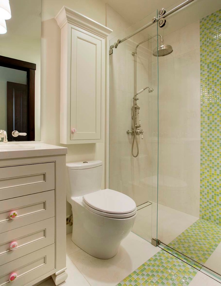Bild på ett litet lantligt badrum för barn, med möbel-liknande, vita skåp, en kantlös dusch, en toalettstol med hel cisternkåpa, flerfärgad kakel, klinkergolv i porslin, ett undermonterad handfat, bänkskiva i kvarts, glasskiva och vita väggar