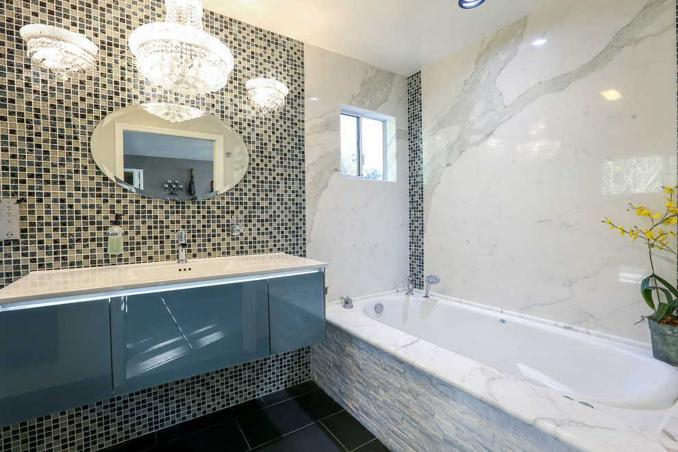 Inredning av ett modernt mellanstort vit vitt en-suite badrum, med släta luckor, ett platsbyggt badkar, en kantlös dusch, en toalettstol med hel cisternkåpa, marmorkakel, vita väggar, klinkergolv i porslin, ett integrerad handfat, med dusch som är öppen, vit kakel, grått golv, bänkskiva i kvarts och grå skåp