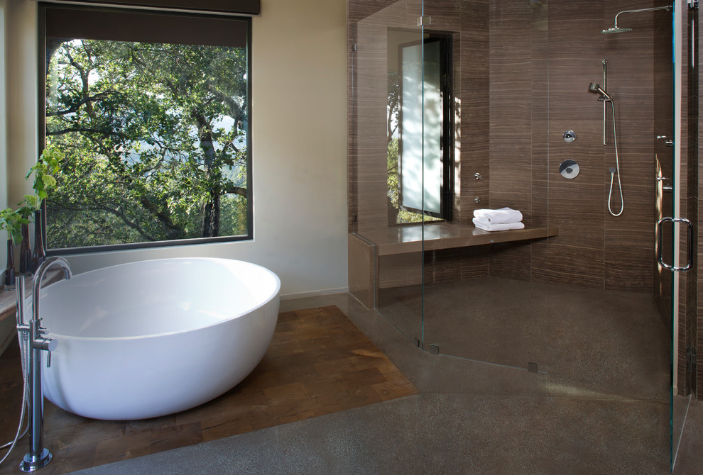 Идея дизайна: главная ванная комната среднего размера в стиле модернизм с отдельно стоящей ванной, душем без бортиков, коричневой плиткой, каменной плиткой, бежевыми стенами и бетонным полом