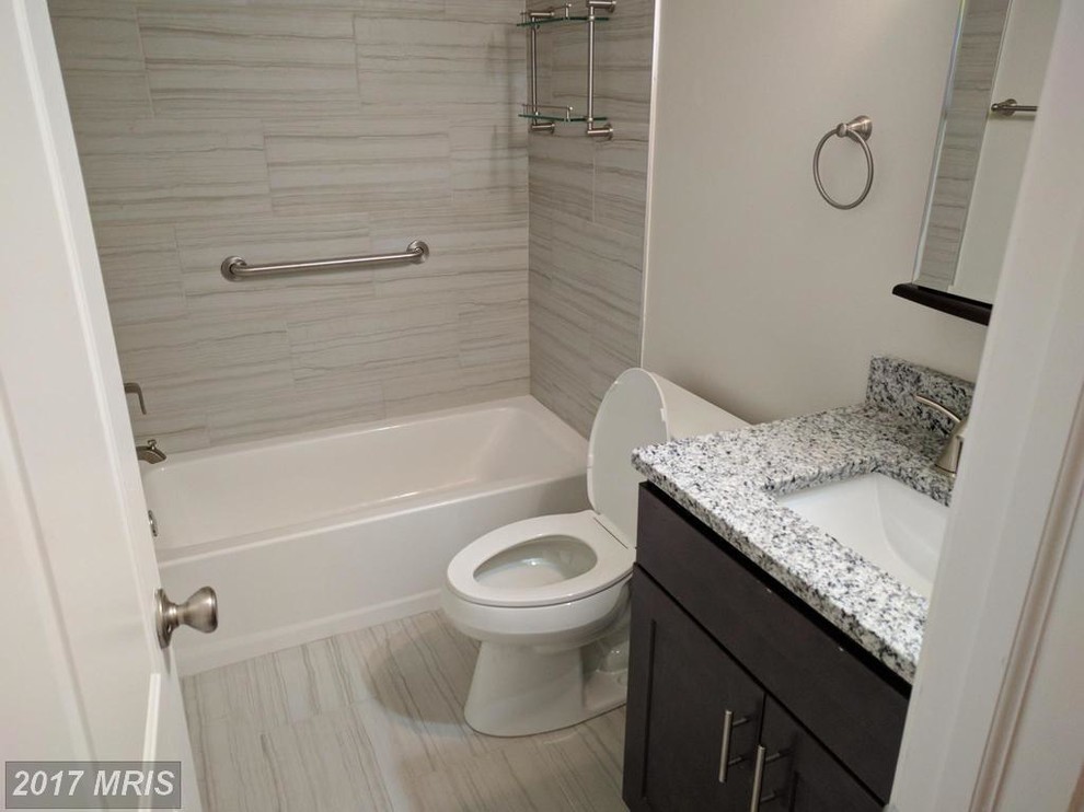 Photo of a small classic ensuite bathroom in DC Metro with shaker cabinets, dark wood cabinets, an alcove bath, a two-piece toilet, white tiles, porcelain tiles, beige walls, porcelain flooring, a submerged sink, granite worktops and white floors.
