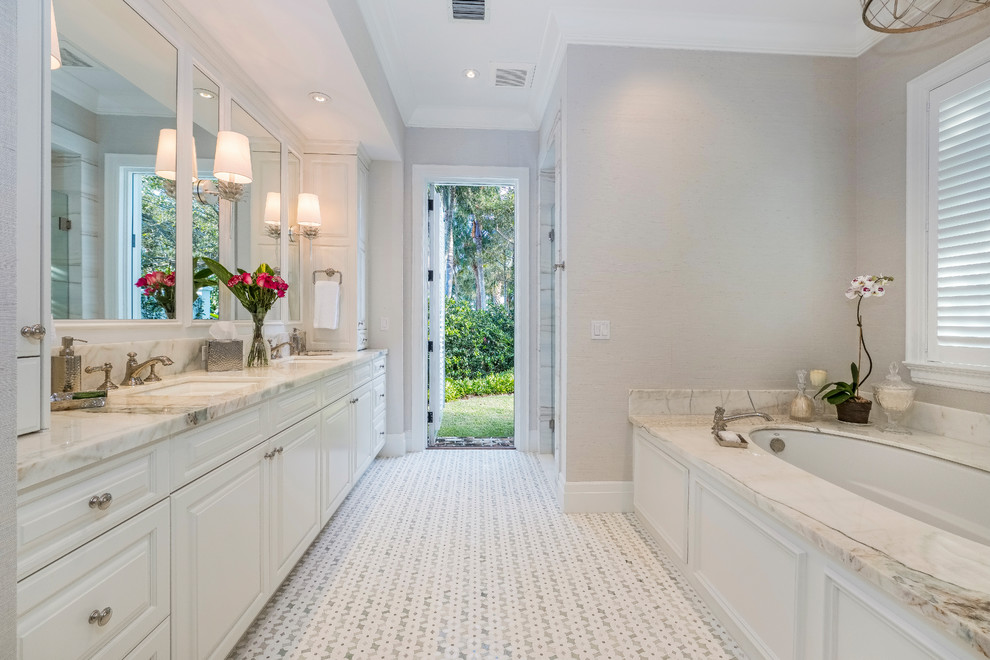 Inspiration for a large timeless master mosaic tile floor and white floor bathroom remodel in Other with raised-panel cabinets, an undermount tub, a one-piece toilet, gray walls, an undermount sink, marble countertops, a hinged shower door, white countertops and white cabinets