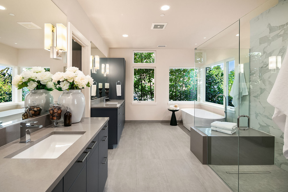 Modernes Badezimmer En Suite mit flächenbündigen Schrankfronten, grauen Schränken, freistehender Badewanne, Eckdusche, beiger Wandfarbe, Unterbauwaschbecken, grauem Boden, Falttür-Duschabtrennung und grauer Waschtischplatte in Seattle