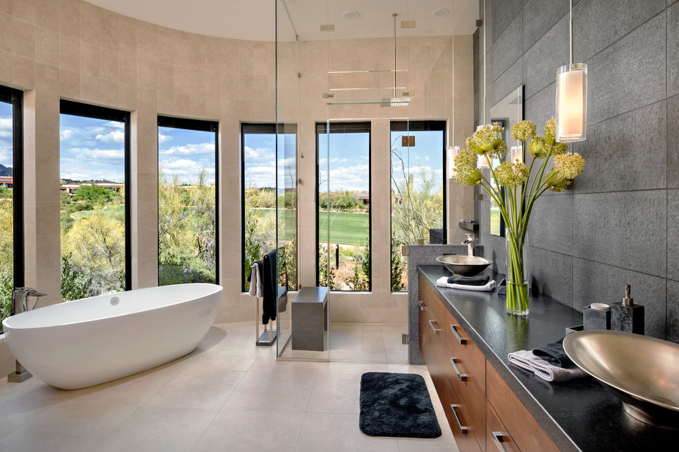 Bild på ett funkis en-suite badrum, med släta luckor, skåp i mörkt trä, ett fristående badkar, en kantlös dusch, svart kakel, beige väggar, ett fristående handfat, beiget golv och dusch med gångjärnsdörr