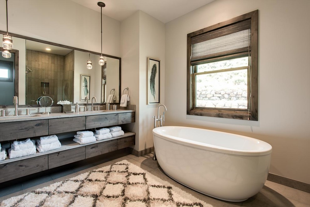 Uriges Badezimmer mit flächenbündigen Schrankfronten, dunklen Holzschränken, freistehender Badewanne, beiger Wandfarbe und Unterbauwaschbecken in Austin