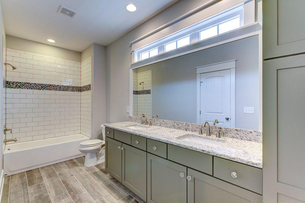 Exempel på ett stort lantligt en-suite badrum, med skåp i shakerstil, grå skåp, ett badkar i en alkov, en dusch/badkar-kombination, en toalettstol med separat cisternkåpa, grå kakel, keramikplattor, grå väggar, klinkergolv i keramik, ett undermonterad handfat och granitbänkskiva