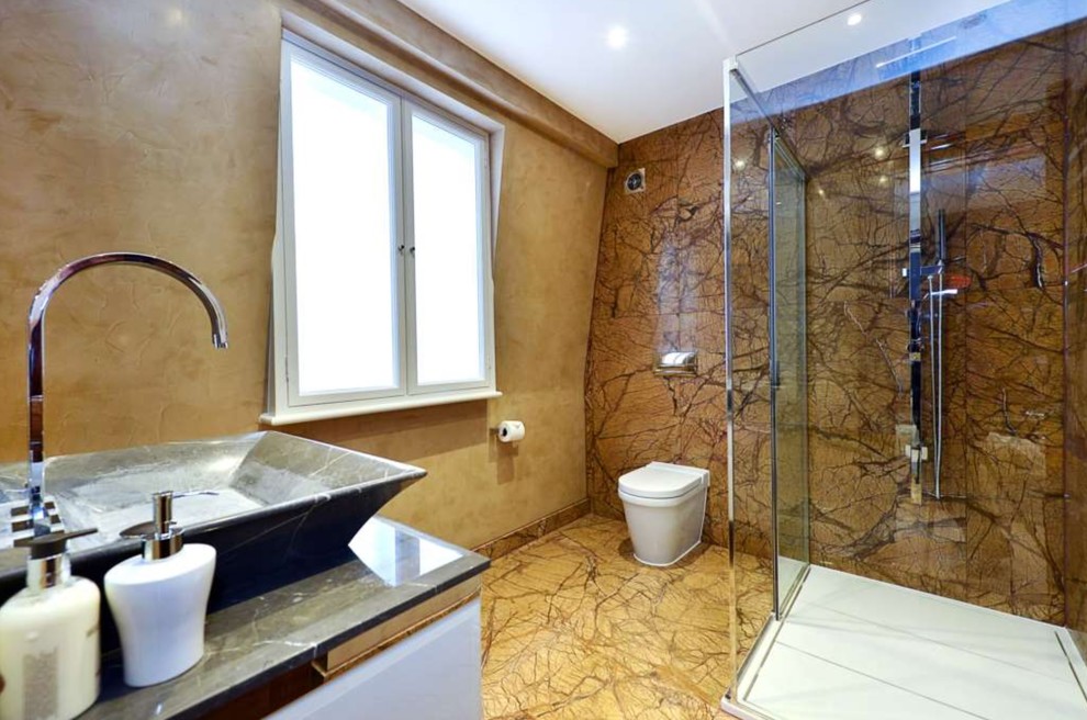 This is an example of a contemporary bathroom in London with a corner shower, a one-piece toilet, brown tiles, brown walls, a vessel sink, brown floors, a sliding door and grey worktops.