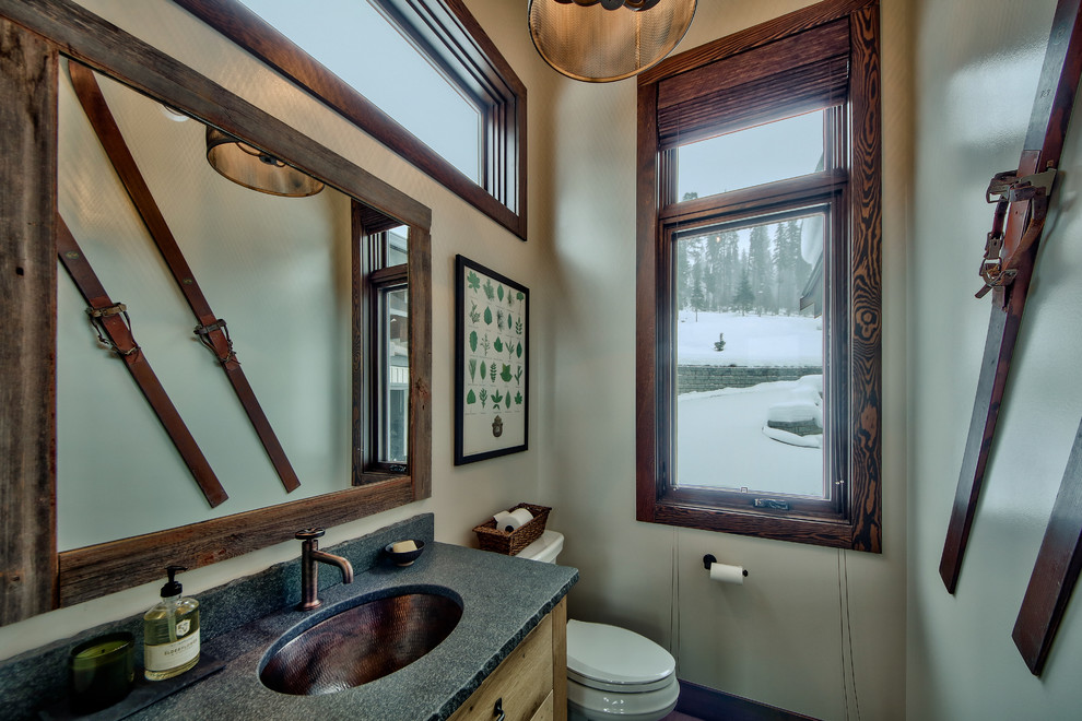 Foto di una stanza da bagno rustica di medie dimensioni con ante lisce, ante in legno chiaro, WC monopezzo, pareti beige, pavimento in cemento, lavabo da incasso e top in cemento