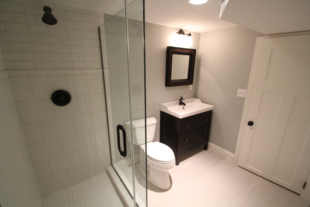 Foto på ett mellanstort vintage badrum med dusch, med släta luckor, skåp i mörkt trä, bänkskiva i akrylsten, en hörndusch, en toalettstol med hel cisternkåpa, vit kakel, porslinskakel, grå väggar och klinkergolv i porslin