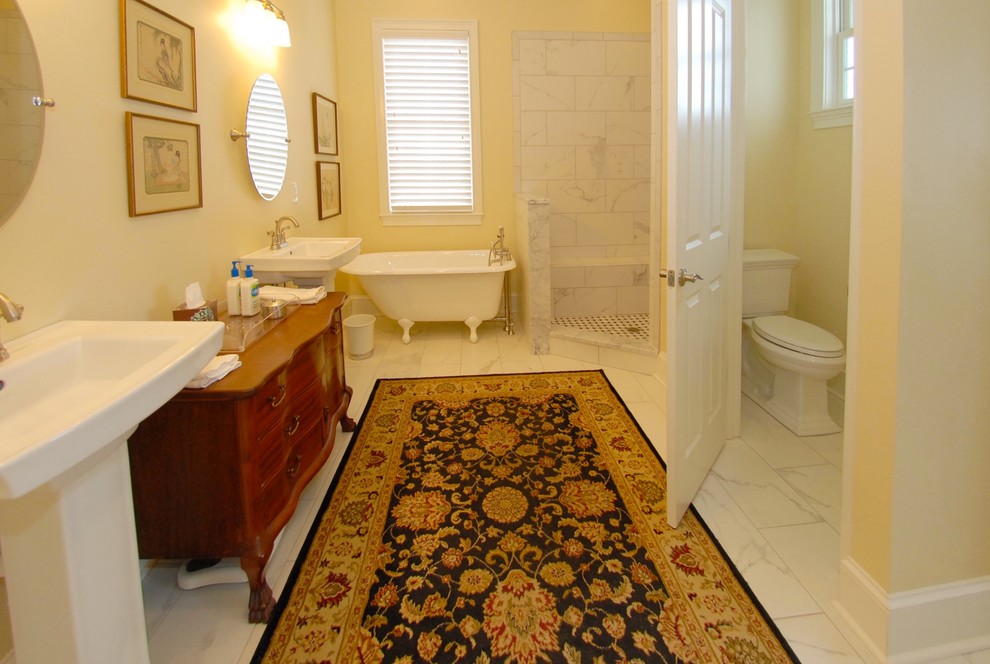 Exemple d'une salle de bain chic en bois brun avec un placard en trompe-l'oeil, une baignoire sur pieds, une douche d'angle, un carrelage gris, un carrelage blanc, du carrelage en marbre, un mur jaune, un sol en marbre, un lavabo de ferme, un plan de toilette en surface solide, un sol blanc et une cabine de douche à porte battante.
