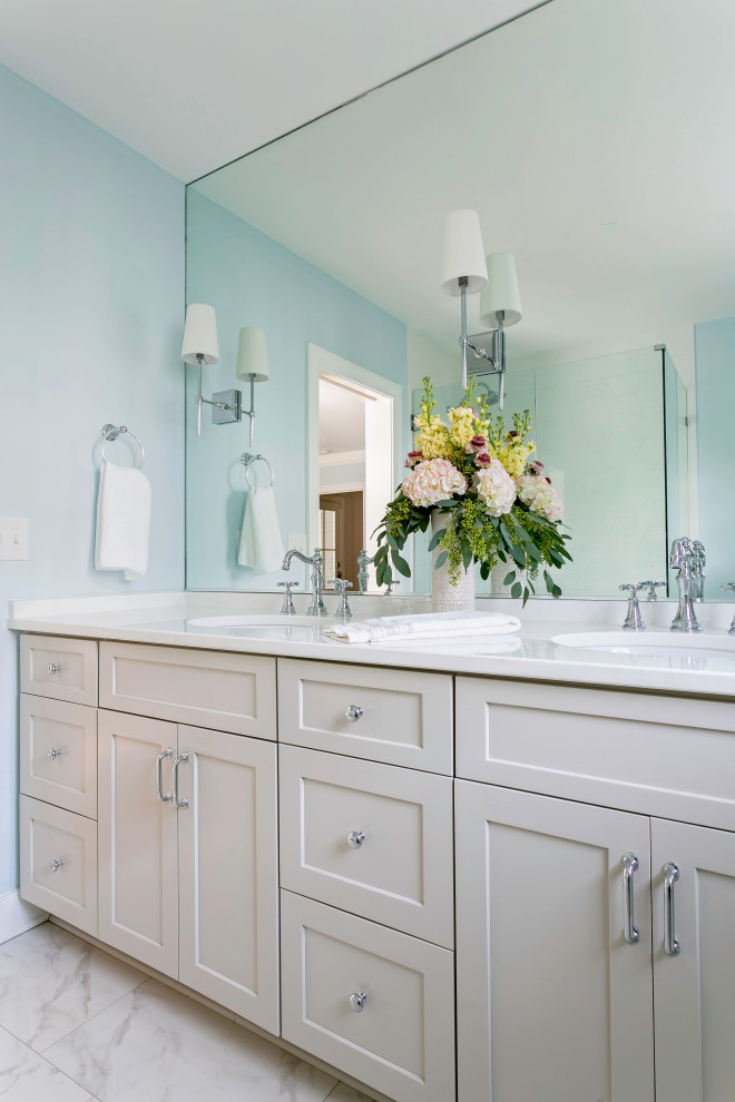 Пример оригинального дизайна: главная ванная комната среднего размера в стиле ретро с плоскими фасадами, бежевыми фасадами, угловым душем, раздельным унитазом, белой плиткой, керамогранитной плиткой, синими стенами, мраморным полом, врезной раковиной, столешницей из искусственного кварца, белым полом, душем с распашными дверями, белой столешницей, тумбой под две раковины и встроенной тумбой