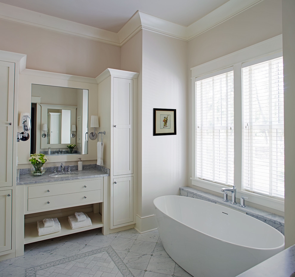 Immagine di una stanza da bagno stile marino con ante in stile shaker, ante bianche, vasca freestanding, piastrelle bianche, pareti beige, lavabo sottopiano, pavimento bianco e top grigio