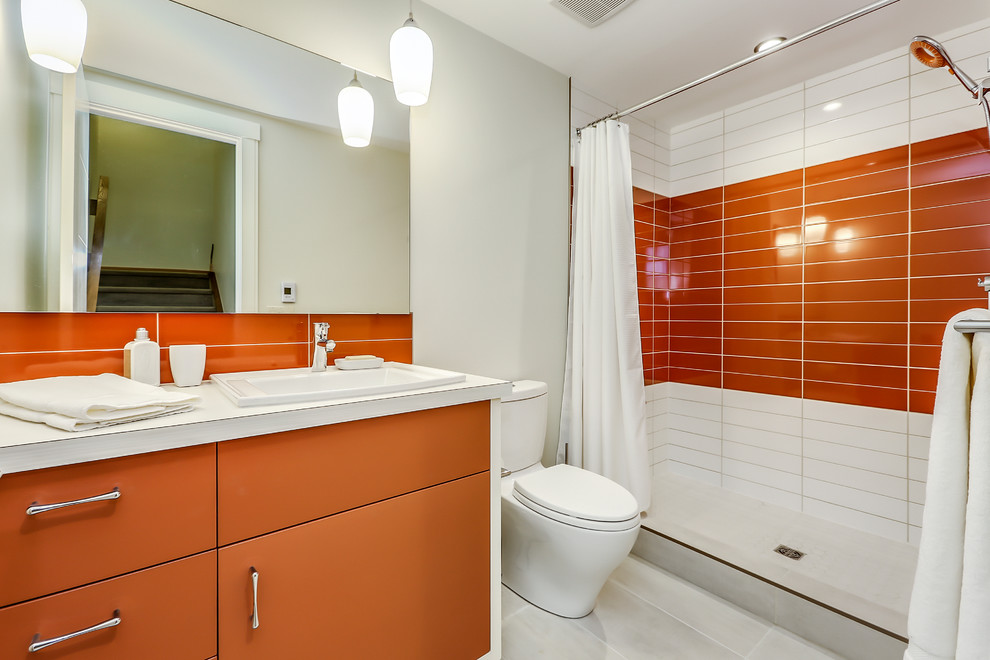 Mittelgroßes Mid-Century Duschbad mit verzierten Schränken, orangefarbenen Schränken, Duschnische, Toilette mit Aufsatzspülkasten, orangen Fliesen, Keramikfliesen, weißer Wandfarbe, Porzellan-Bodenfliesen, Einbauwaschbecken, Laminat-Waschtisch, weißem Boden und Duschvorhang-Duschabtrennung in Calgary
