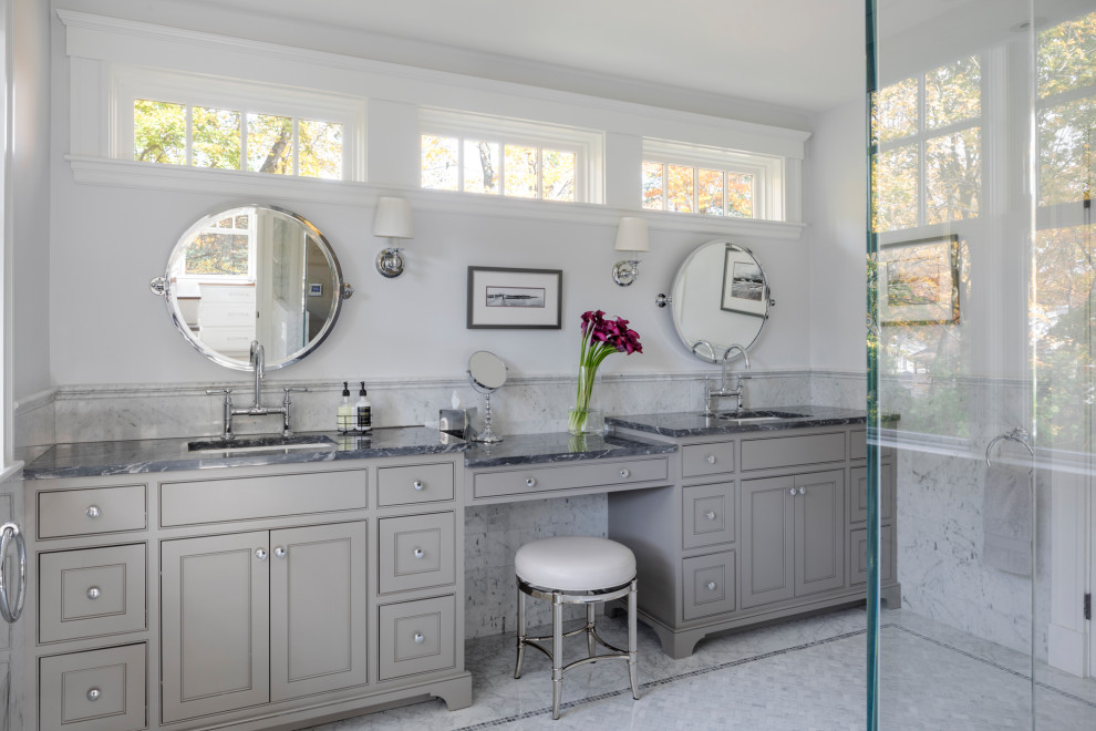 Пример оригинального дизайна: большая главная, серо-белая ванная комната в стиле неоклассика (современная классика) с фасадами с утопленной филенкой, серыми фасадами, угловым душем, унитазом-моноблоком, серой плиткой, плиткой мозаикой, серыми стенами, полом из мозаичной плитки, мраморной столешницей, серым полом, душем с распашными дверями, врезной раковиной и серой столешницей