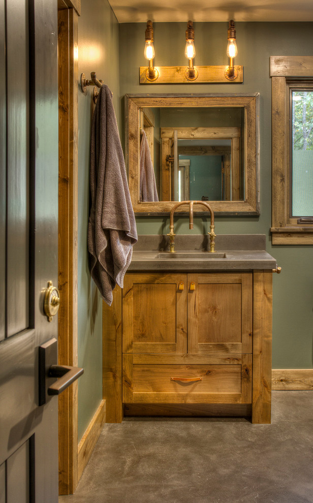 Modelo de cuarto de baño rústico con armarios estilo shaker, puertas de armario de madera oscura, paredes verdes, suelo de cemento, suelo gris y encimeras grises