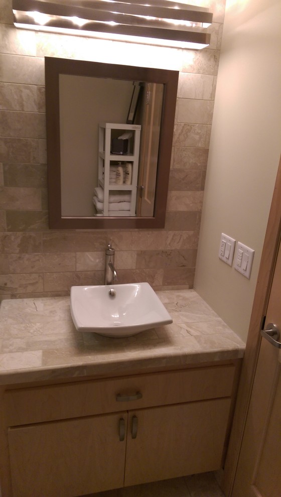 Amerikansk inredning av ett mellanstort en-suite badrum, med ett konsol handfat, luckor med infälld panel, kaklad bänkskiva, en dusch i en alkov, en toalettstol med separat cisternkåpa, brun kakel, stenkakel, bruna väggar och travertin golv