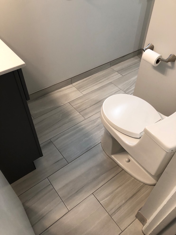 Small transitional porcelain tile and gray floor alcove shower photo in Chicago with furniture-like cabinets, blue cabinets, a one-piece toilet, gray walls, an integrated sink, solid surface countertops, a hinged shower door and white countertops
