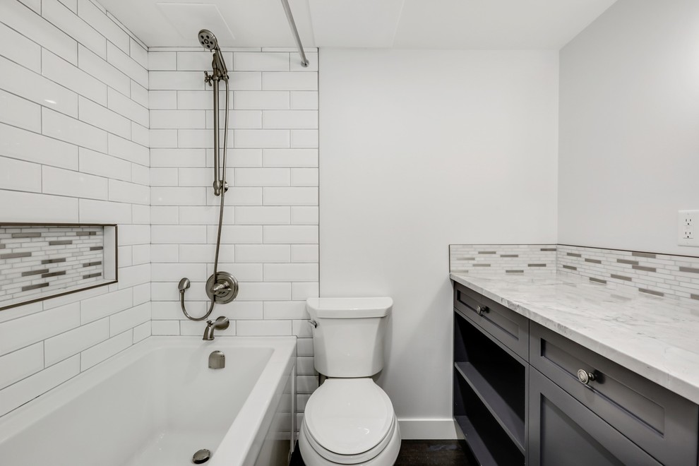 Cette photo montre une petite salle de bain principale chic avec un placard à porte shaker, des portes de placard marrons, une baignoire posée, un combiné douche/baignoire, WC séparés, un carrelage multicolore, mosaïque, un mur gris, un sol en liège, un lavabo encastré, un plan de toilette en quartz, un sol marron, une cabine de douche avec un rideau et un plan de toilette blanc.