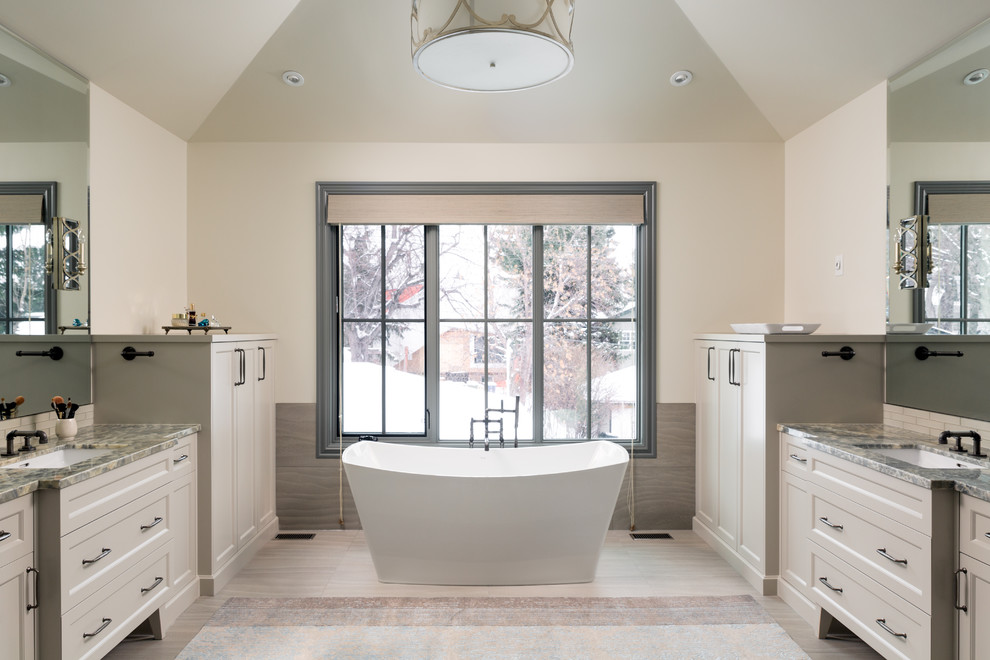 Klassisk inredning av ett en-suite badrum, med beige skåp, ett fristående badkar, beige väggar, ett undermonterad handfat, beiget golv och skåp i shakerstil