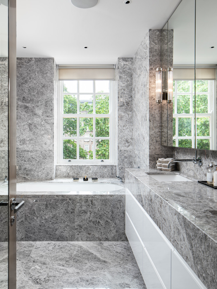 Modelo de cuarto de baño contemporáneo con armarios con paneles lisos, puertas de armario blancas, bañera encastrada sin remate, lavabo bajoencimera, suelo gris y encimeras grises