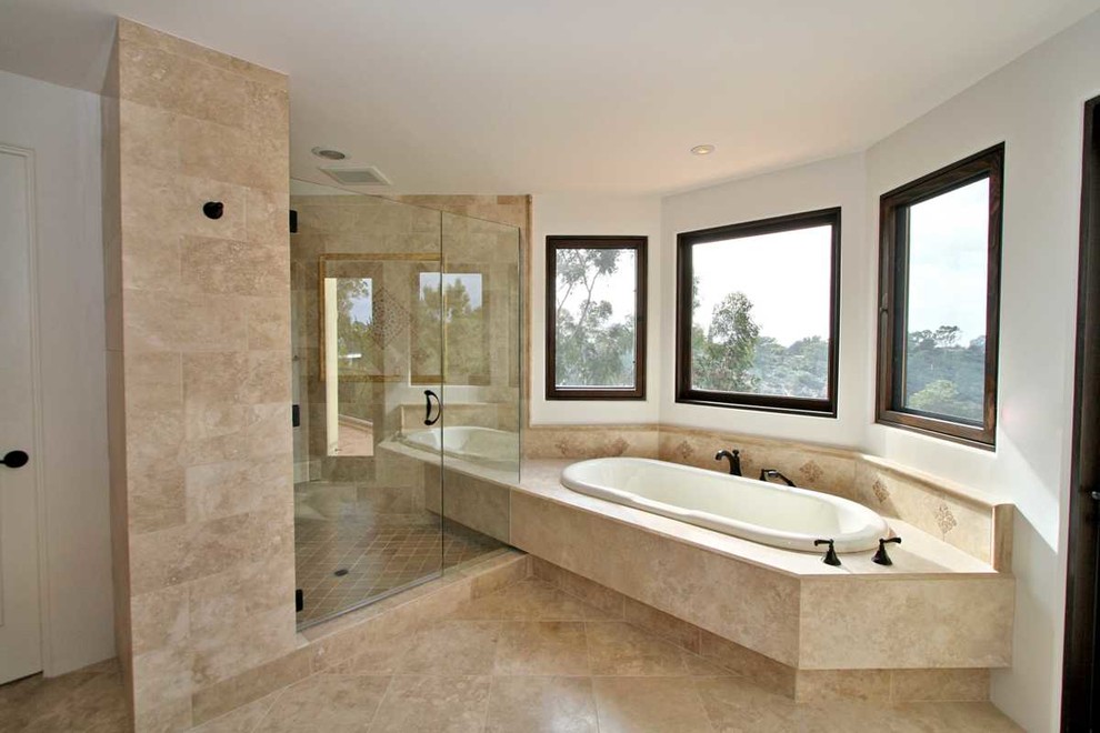 Inspiration for a large mediterranean master beige tile and travertine tile travertine floor and beige floor bathroom remodel in San Diego with recessed-panel cabinets, medium tone wood cabinets, a one-piece toilet, yellow walls, a vessel sink, limestone countertops and a hinged shower door