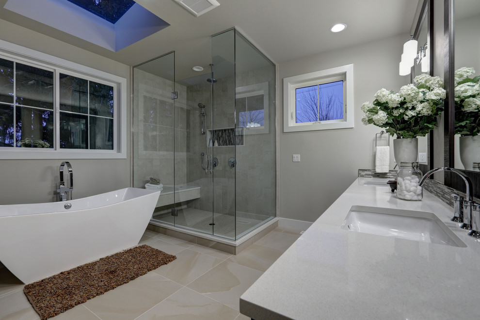 Стильный дизайн: огромная главная ванная комната в стиле модернизм с отдельно стоящей ванной, угловым душем, серыми стенами, полом из керамогранита, врезной раковиной, столешницей из искусственного кварца, бежевым полом, душем с распашными дверями и серой столешницей - последний тренд