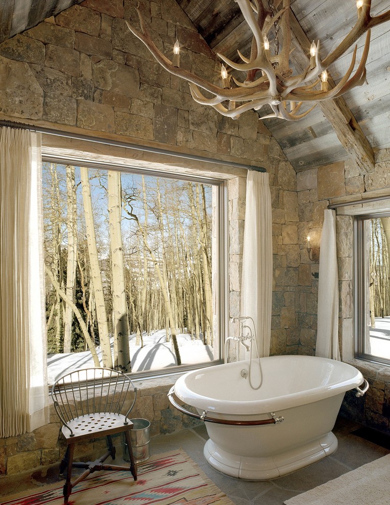 Rustikales Badezimmer mit freistehender Badewanne und Steinwänden in Denver