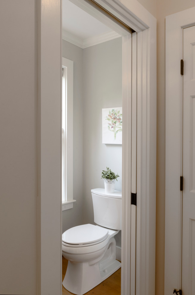 Modelo de cuarto de baño de estilo de casa de campo pequeño con lavabo con pedestal, armarios abiertos, sanitario de una pieza y suelo de madera clara