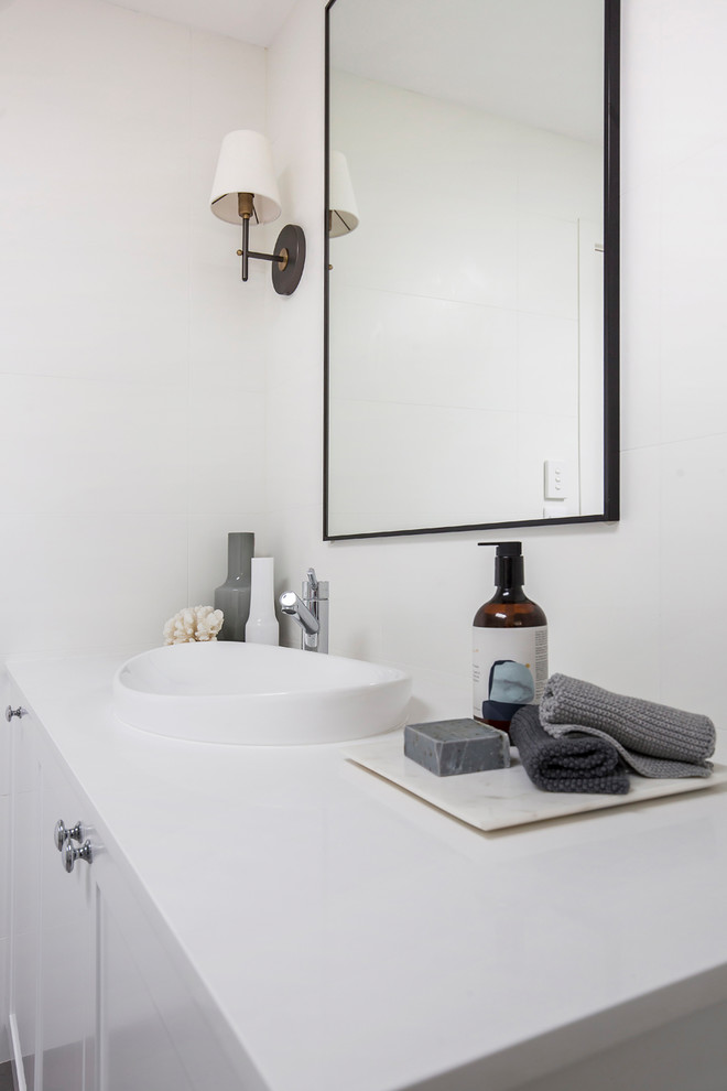 Design ideas for a large contemporary ensuite bathroom in Sydney with shaker cabinets, white cabinets, a freestanding bath, a walk-in shower, a wall mounted toilet, white tiles, porcelain tiles, white walls, porcelain flooring, an integrated sink, engineered stone worktops, grey floors, an open shower and white worktops.